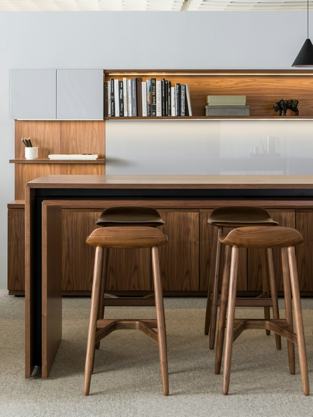 Six Crosshatch Stools with a medium finish provide seating for a standing-height Peer Table in an interaction space that includes a Domino Storage sideboard.