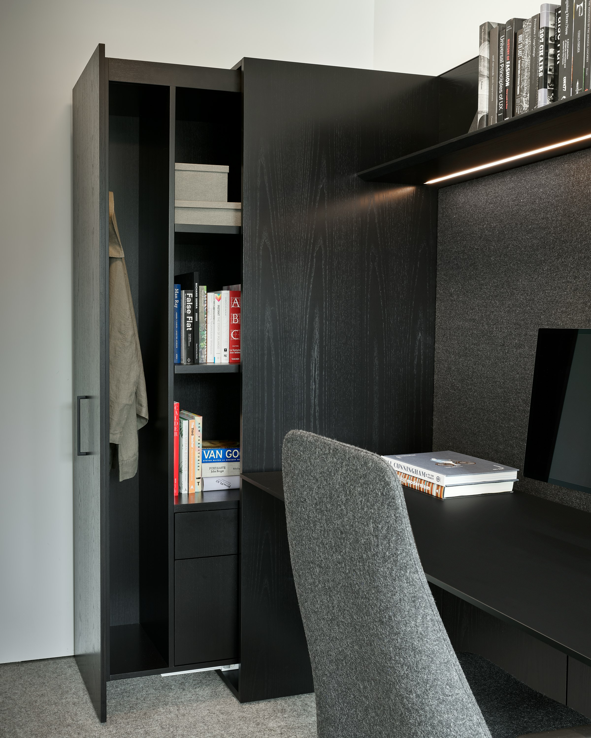 Geiger One Casegoods Private Office partially open vertical pull-out wardrobe in Ebonized Flat Cut Ash, viewed at an angle in a private office setting.