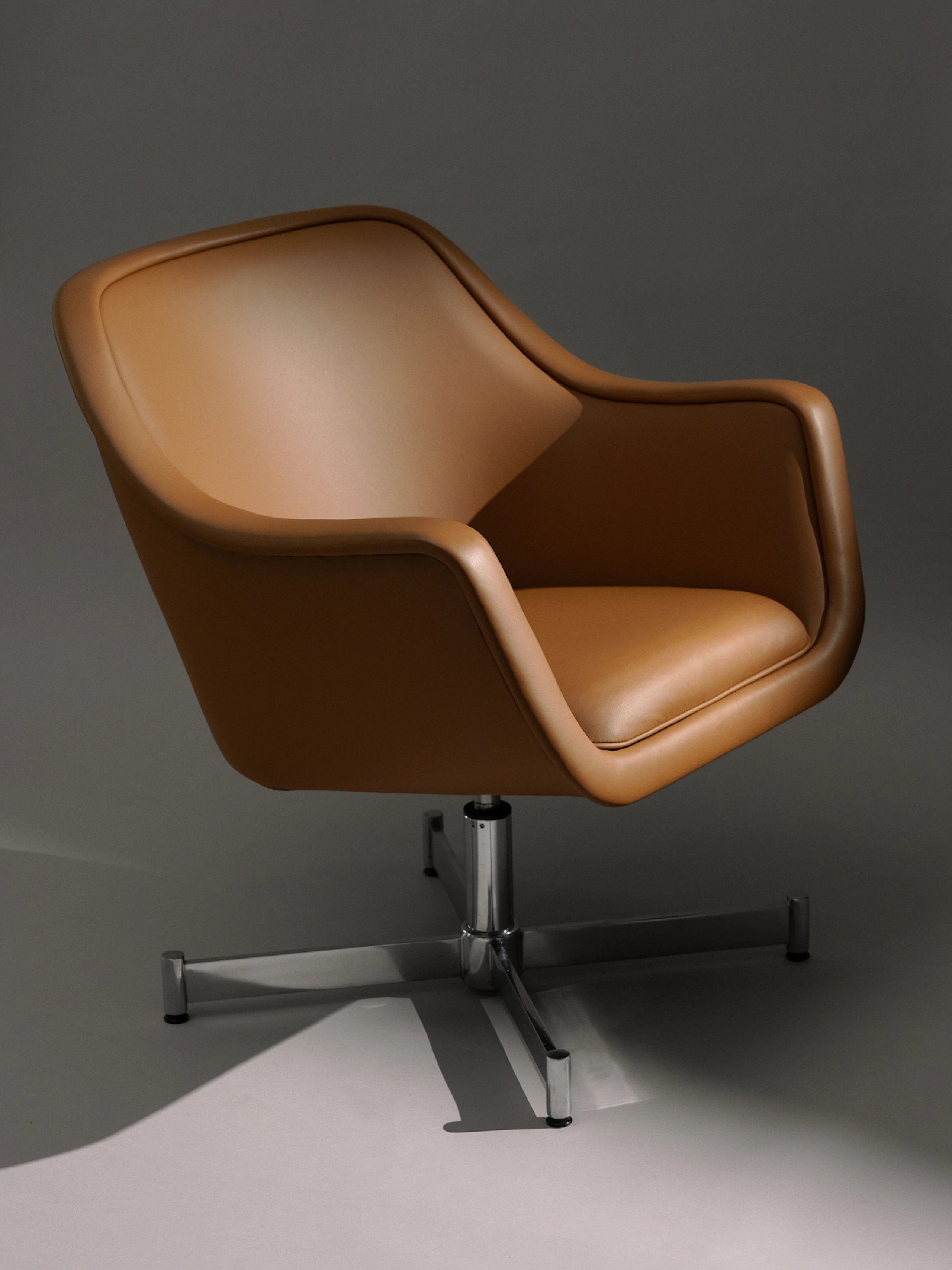 Angle view of Bumper Lounge Chair with chrome base and toffee leather