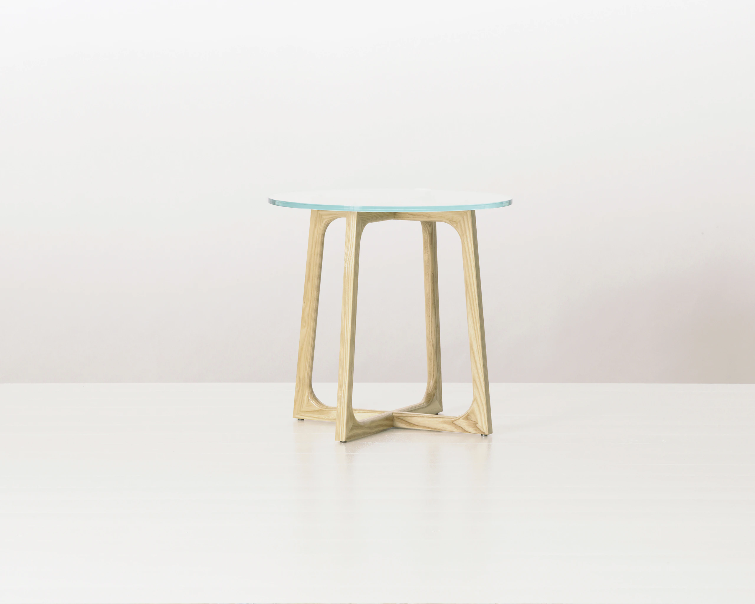 A round Loophole side table with a glass top and an light-ash base.