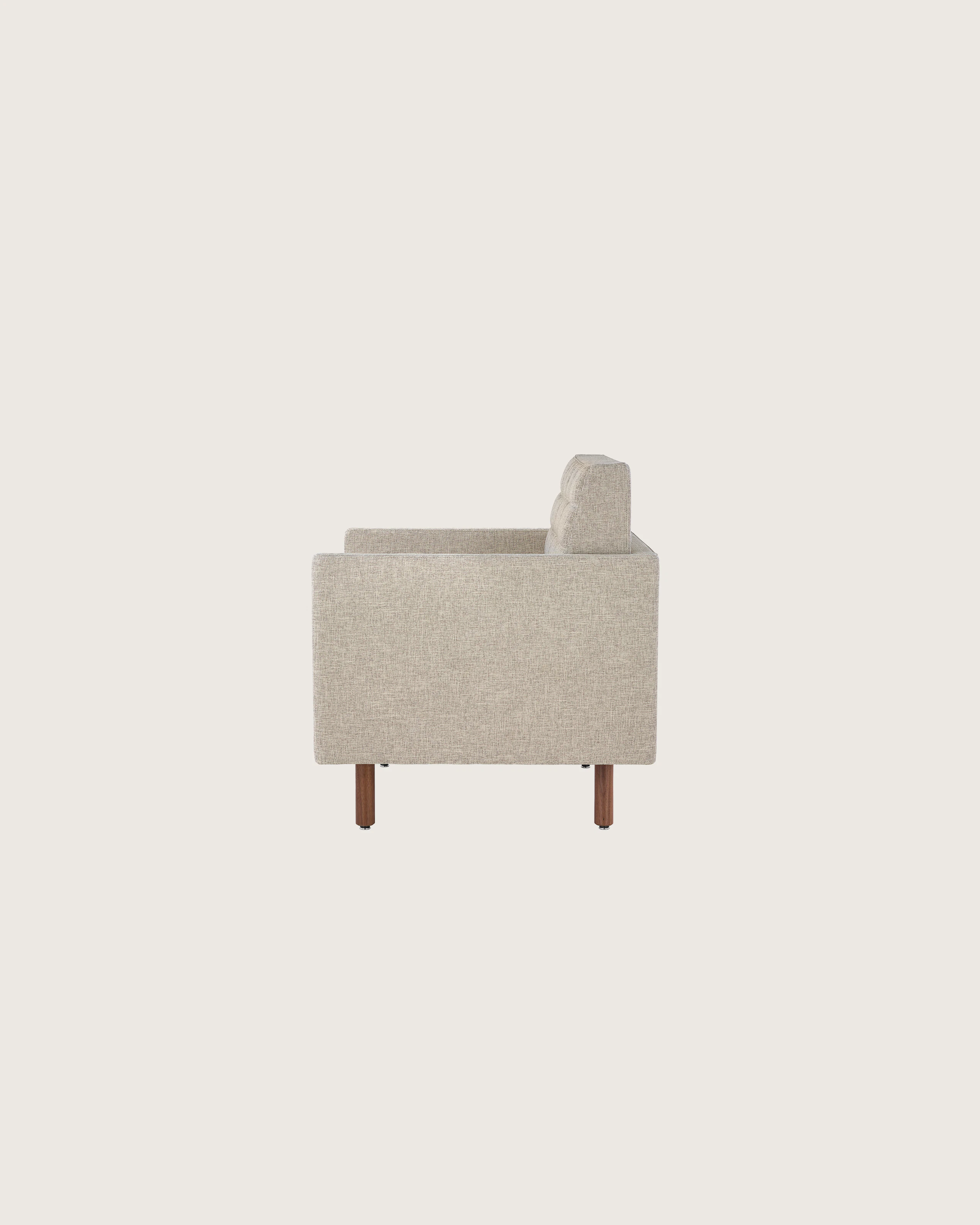 Profile view of a quilted Tuxedo Classic club chair upholstered in bone-colored fabric.