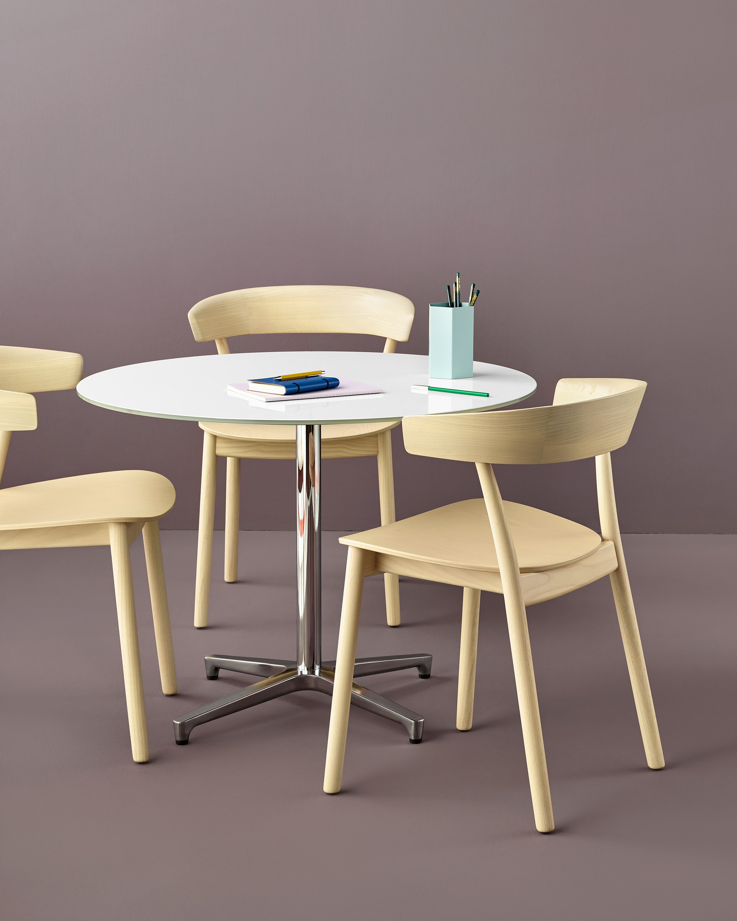 Three all-wood Leeway side chairs surround a round table with a white top and silver column.