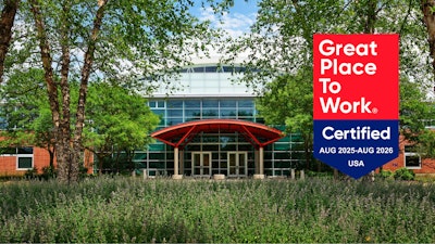 An exterior view of the MillerKnoll Greenhouse building overlayed with a red and blue Great Place To Work Certified Aug 2025 - Aug 2026 badge