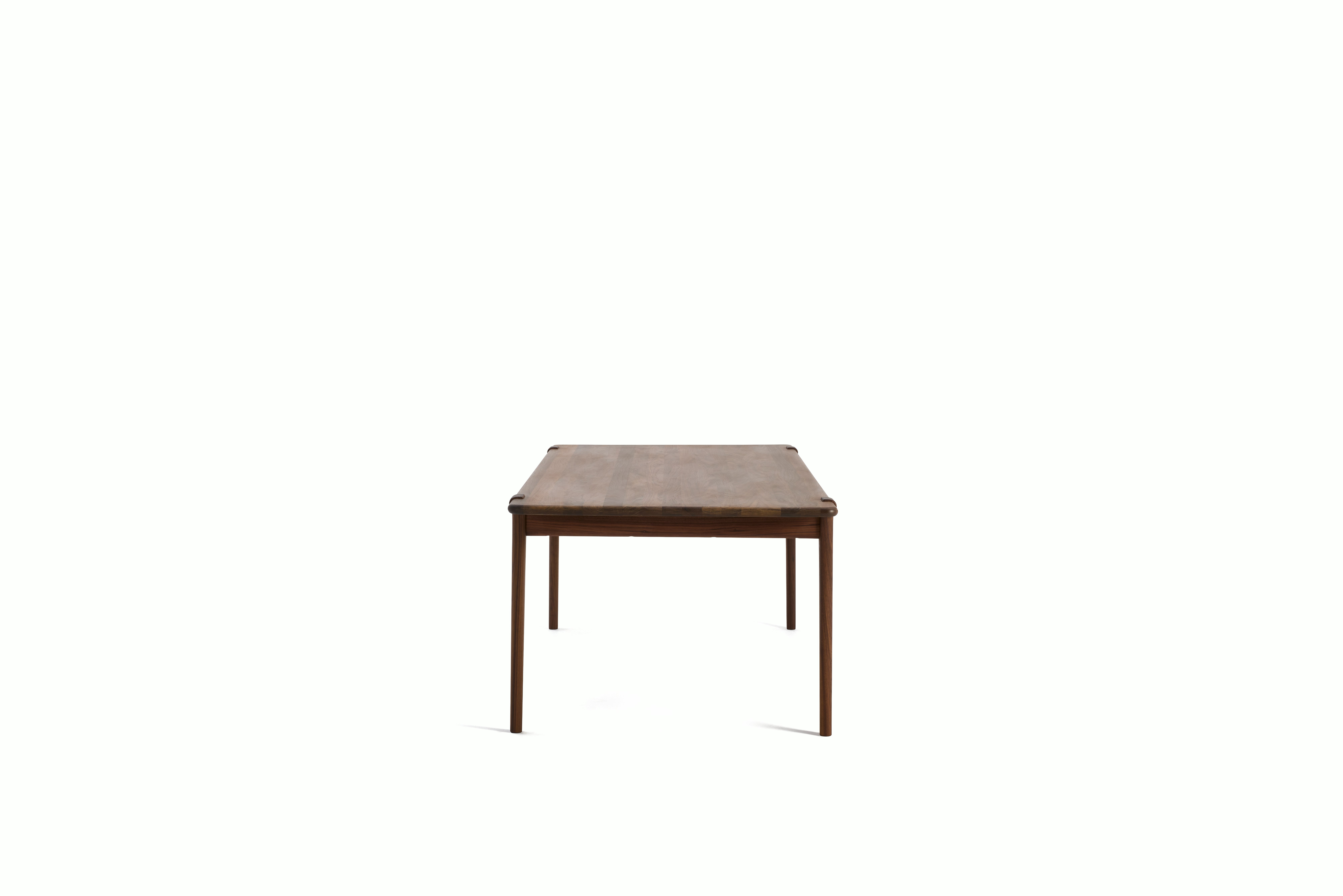An Otto Dining Table in Walnut viewed from the side.