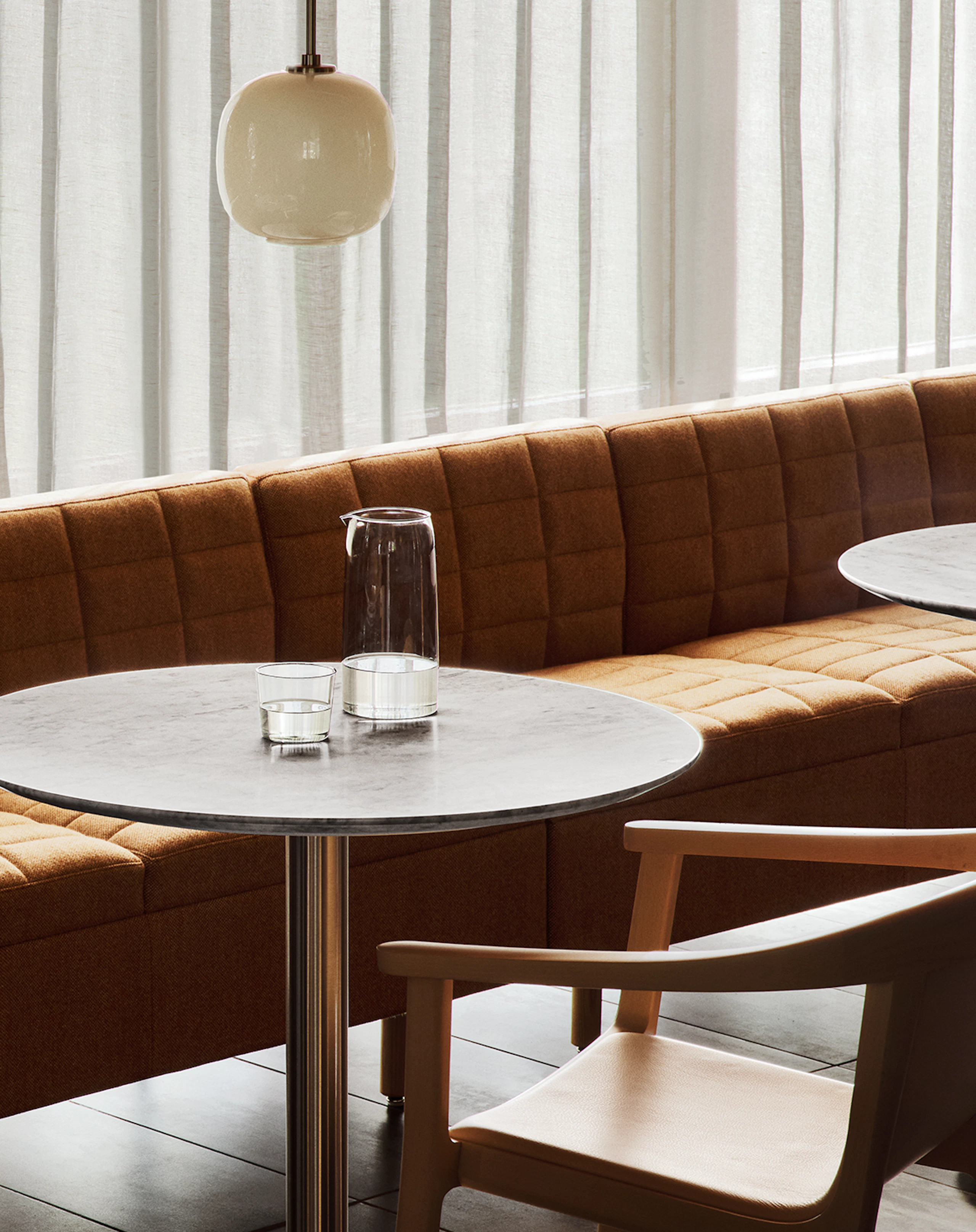 Lijn Armchairs designed by Carole Baijings in a cafe setting with Tuxedo Classic Lounge benching and cafe tables, viewed at an angle.
