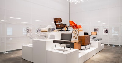 Classic pieces of furniture from the MillerKnoll collective, such as an orange Knoll Womb Chair and black Knoll Barcelona Chair, arranged on white pedestals at the MillerKnoll Archives