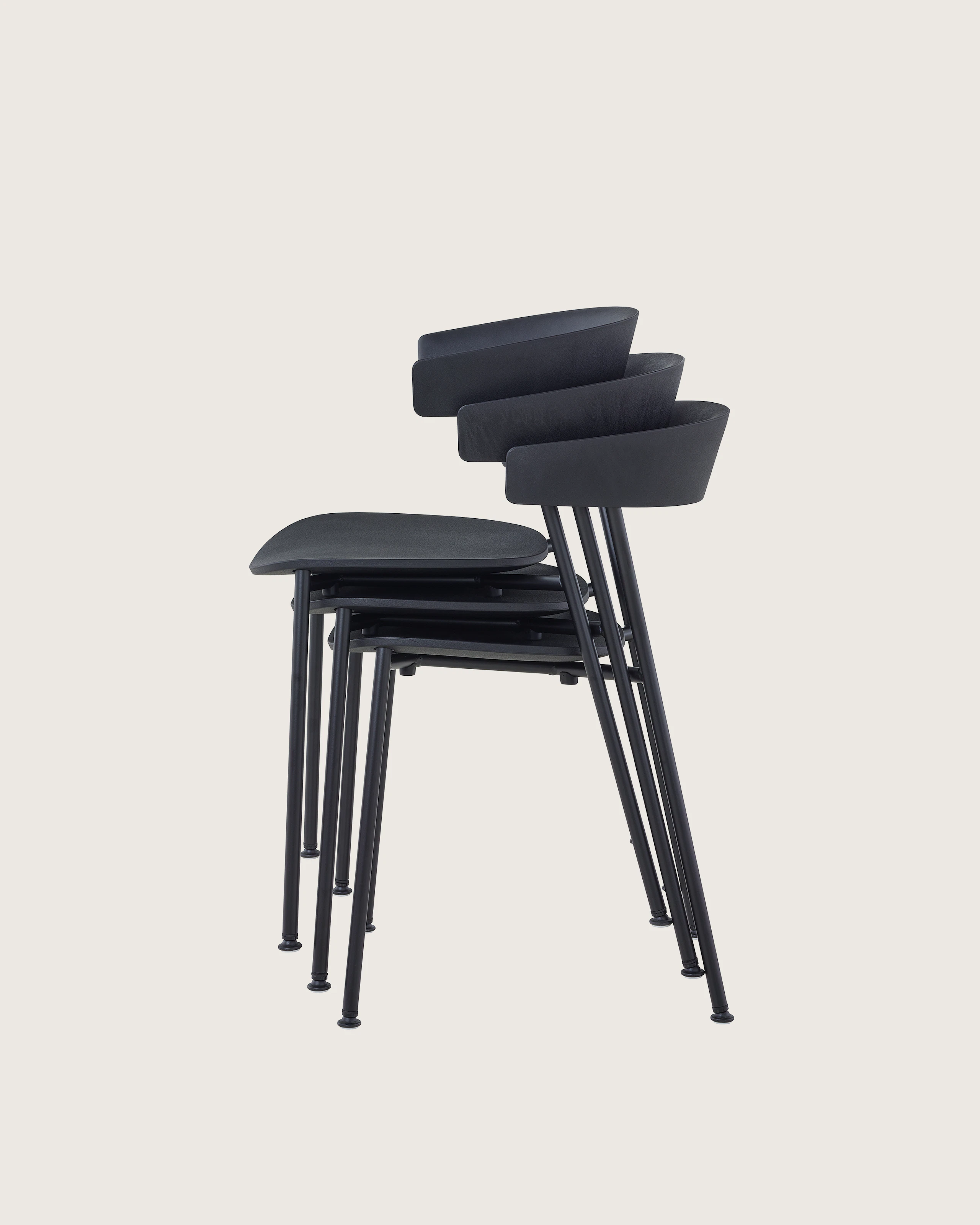 A profile view of black Leeway Chairs stacked three high.