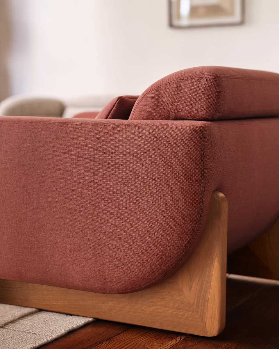 Side profile of dark green sofa with head cushion and curved back.