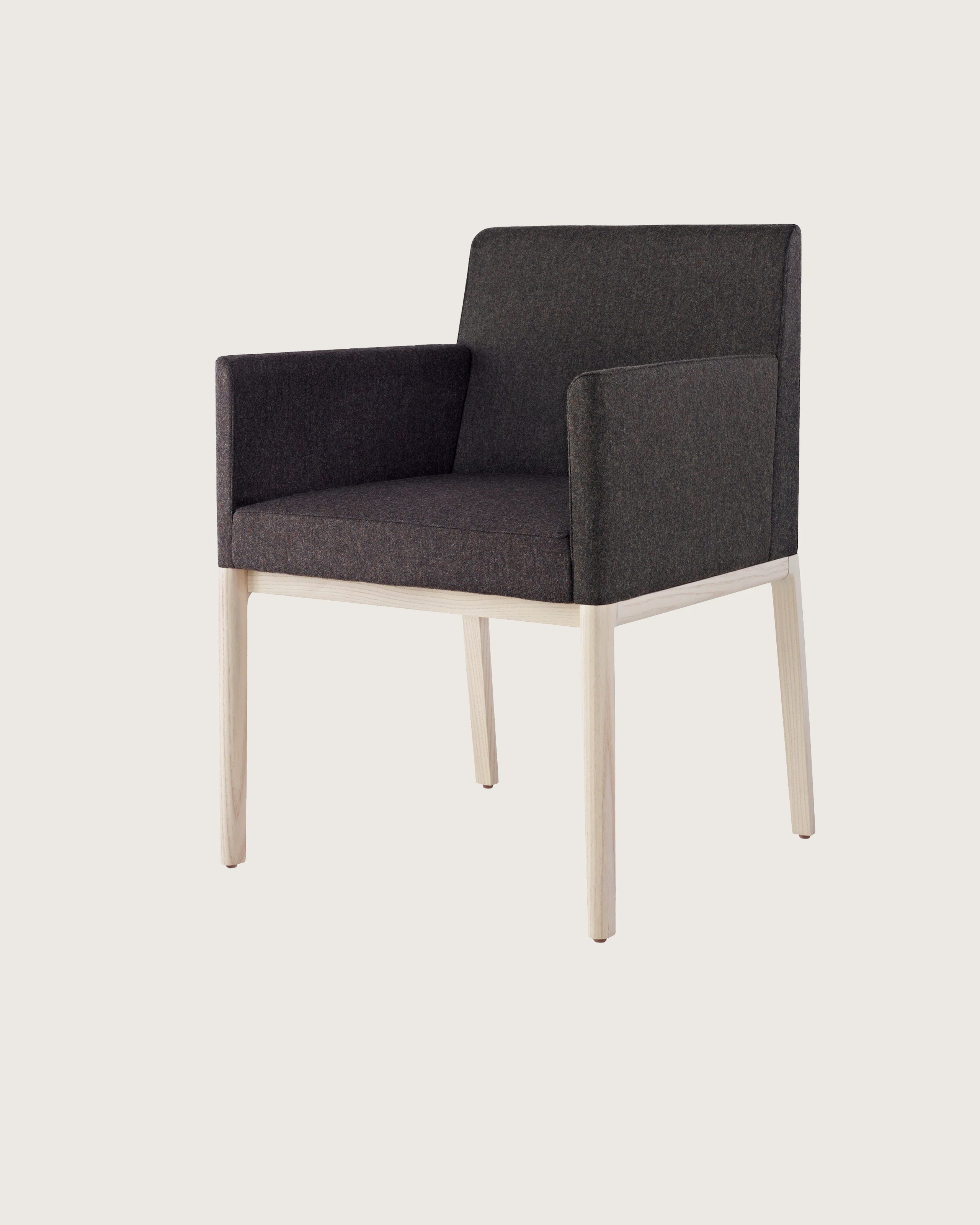Angled view of a Nessel side chair with wraparound arms, showing the precision upholstery and wood craftsmanship.