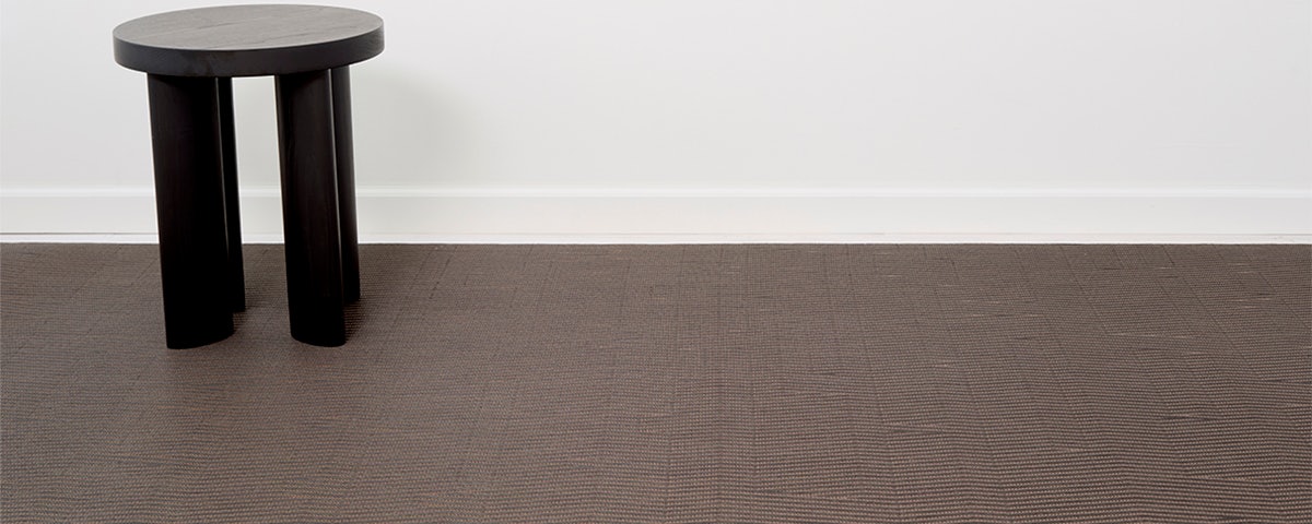 Closeup image of a Dun Rug with a black wooden stool