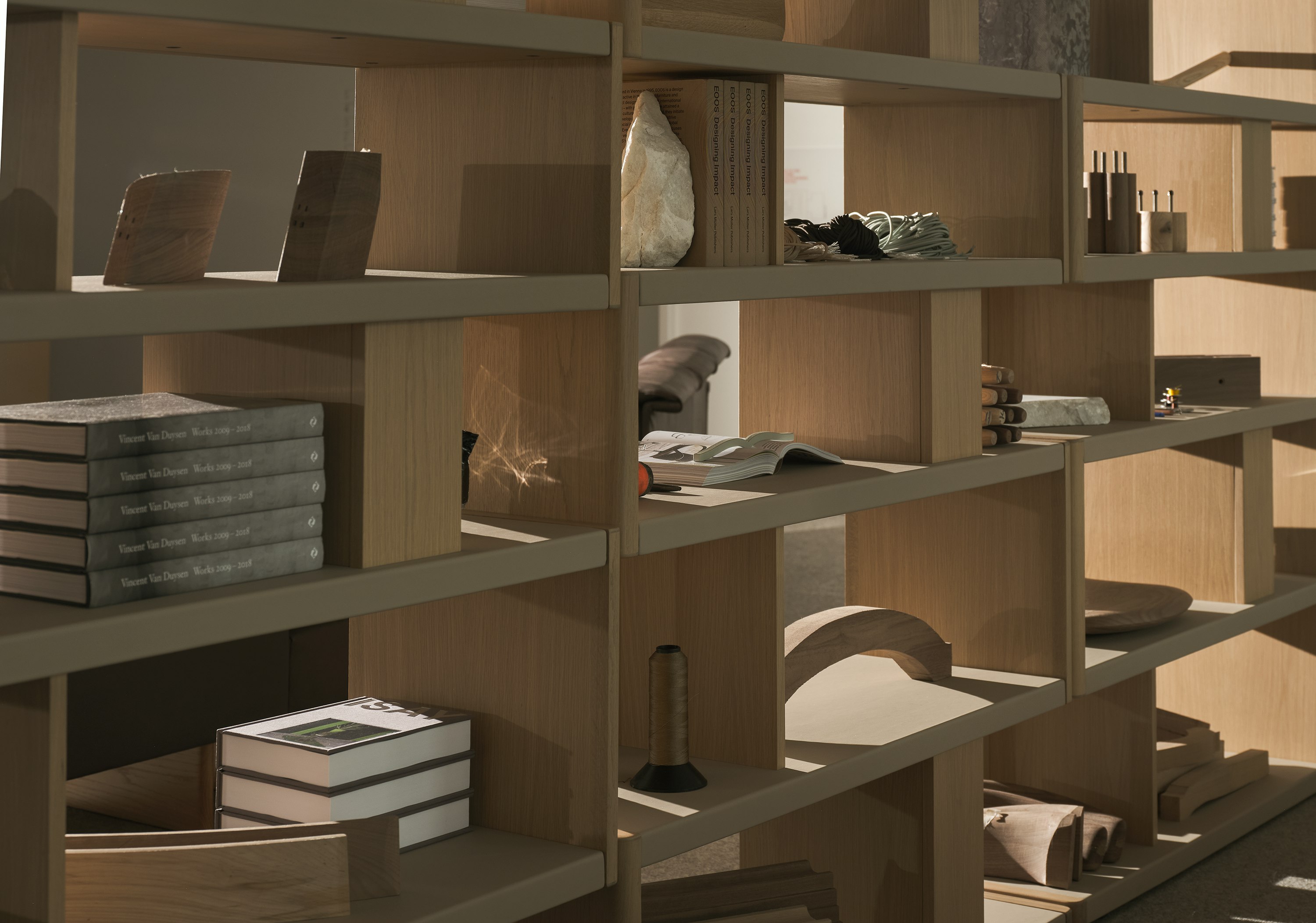 Various New Canaan Tall Bookshelves in Light Oak wrapped with Bristol Leather in Champagne arranged side by side and styled with various objects, viewed at an angle.