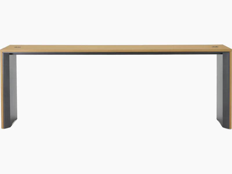 A narrow communal Headway table at standing height with a medium light wood top and dark gray base.