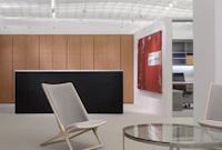 A beige Scissor Chair complements a round Metal Series coffee table in a contemporary reception space.