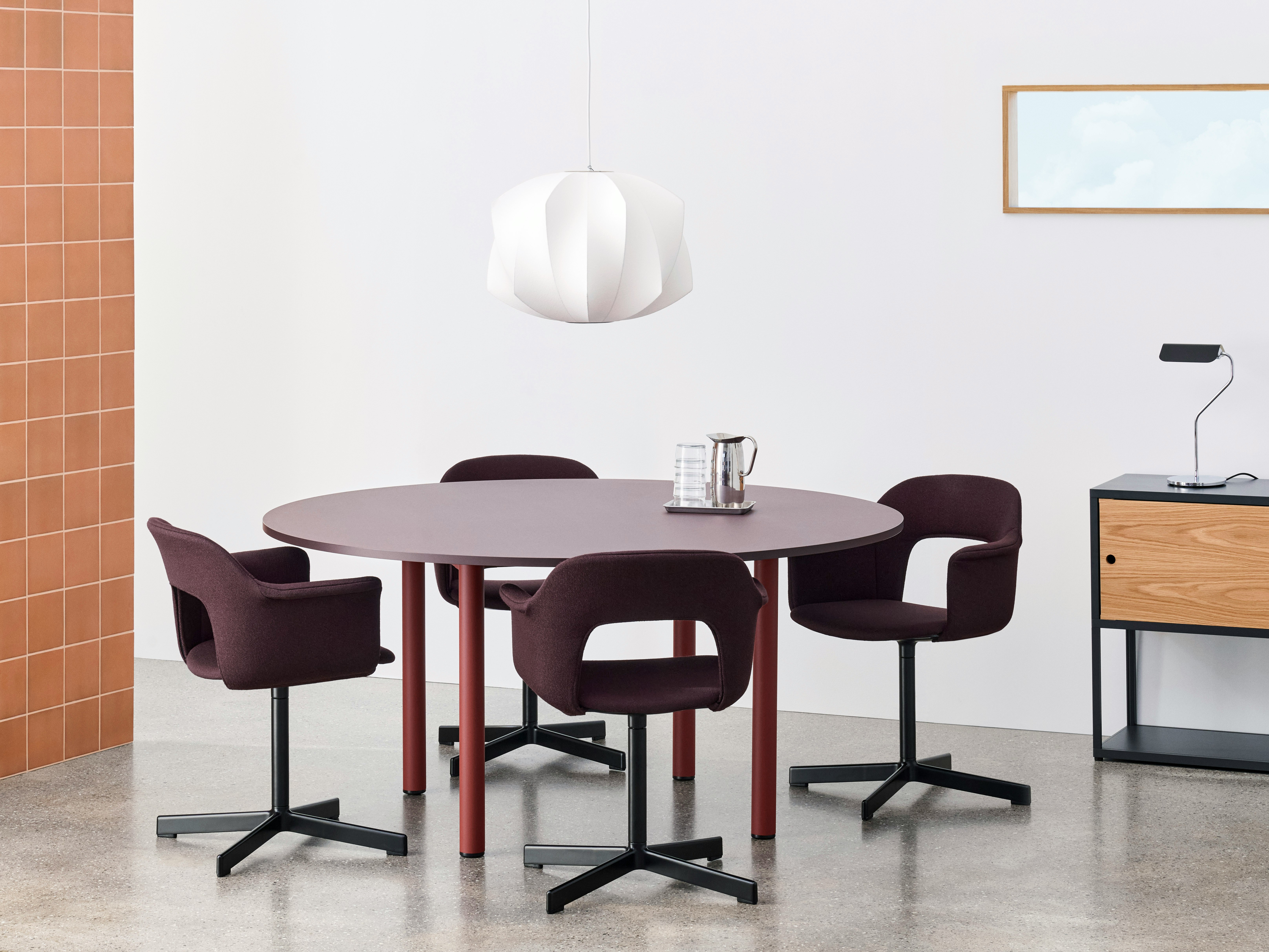 Annex round table, staged with layout chairs and white pendant light in dining setting.