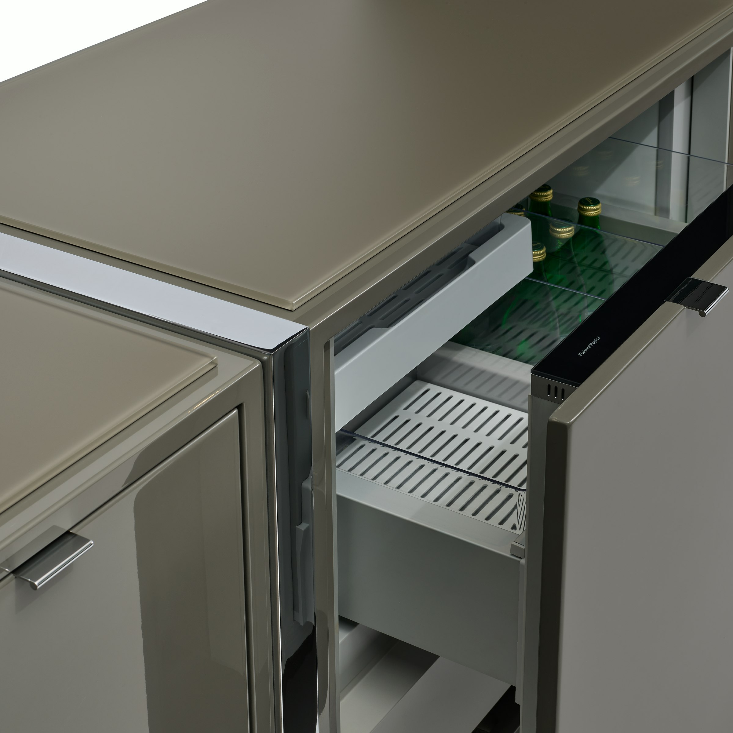 Detail view of an open fridge drawer on a light grey Highline Credenza with polished chrome details, viewed at an angle.