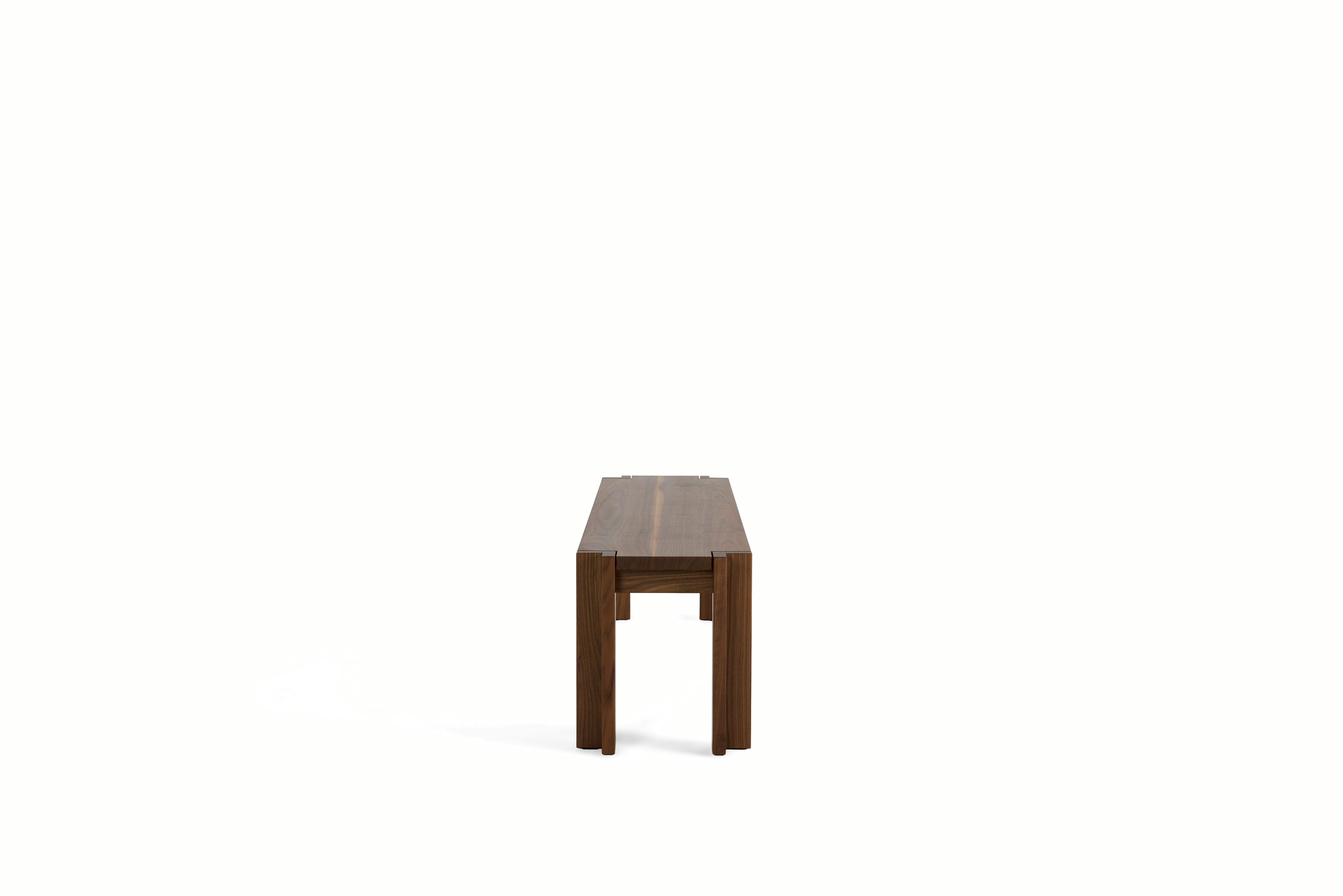 A Utzon Dining Bench in Walnut viewed from the side.