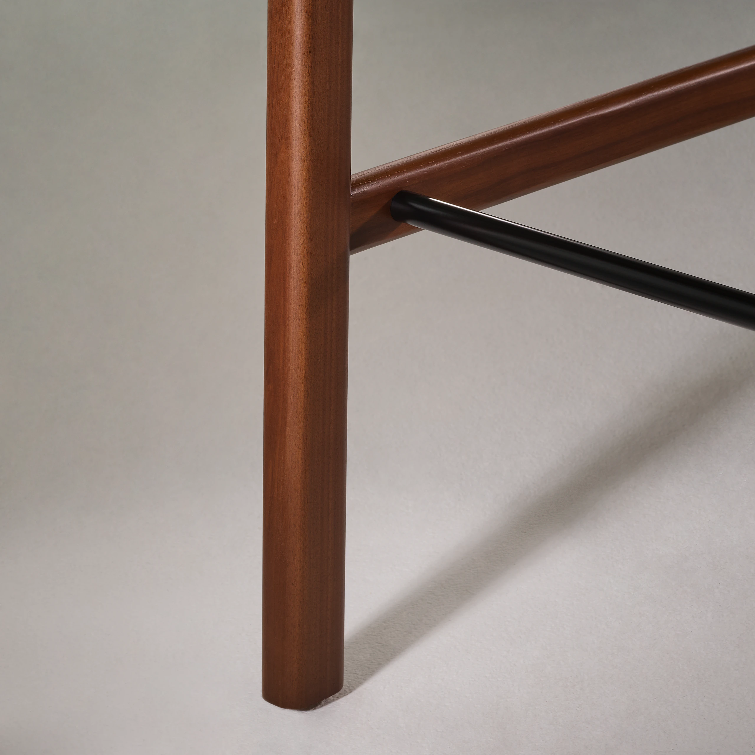 Lijn Stool by Carole Baijings for Geiger in Persian Walnut frame upholstered with Maharam Hue Leather in Bittersweet, detail shot on a light background.