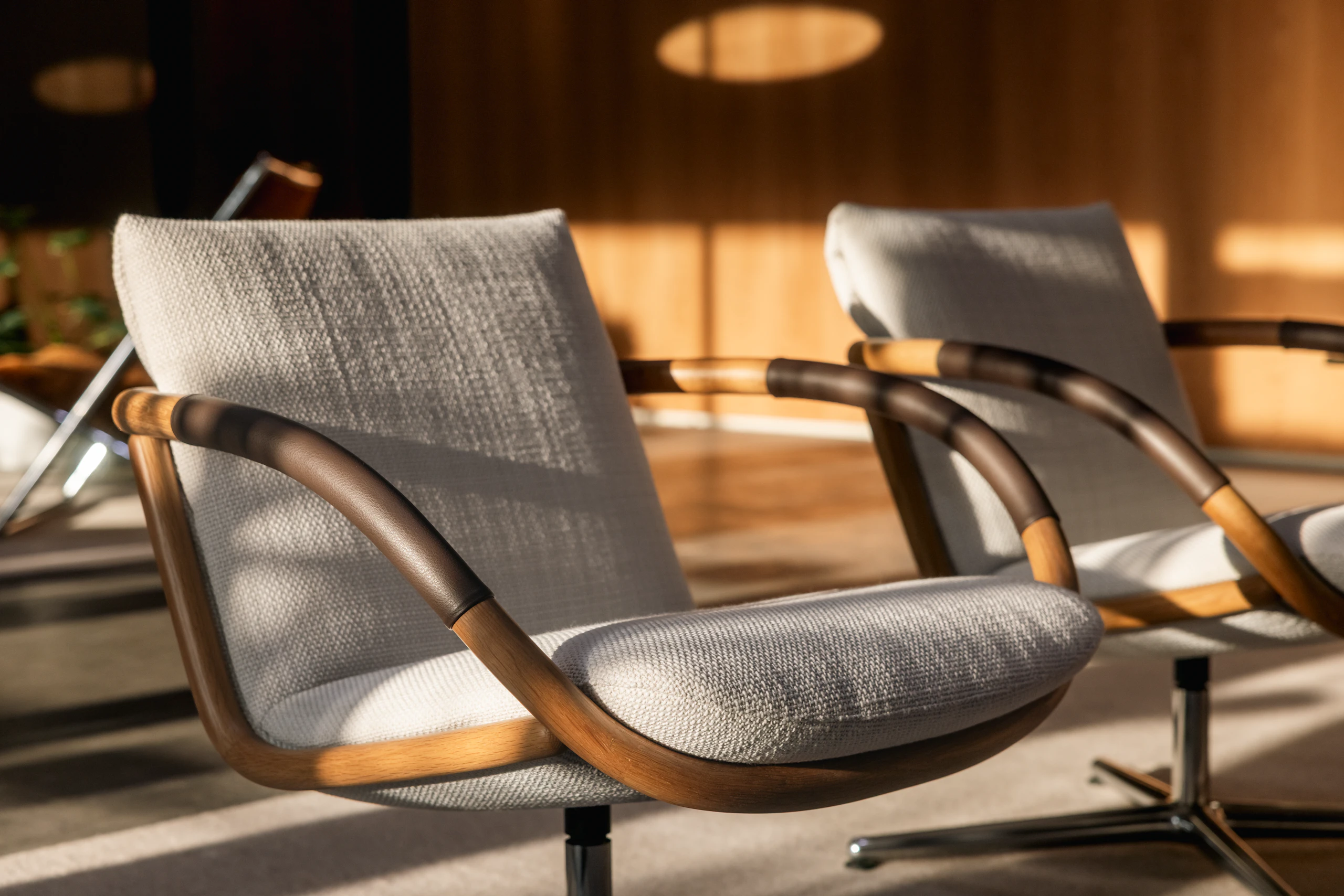 Two Full Loop Lounge Chairs upholstered with Capri in Snow with Oak frames, viewed at an angle in a showroom setting.