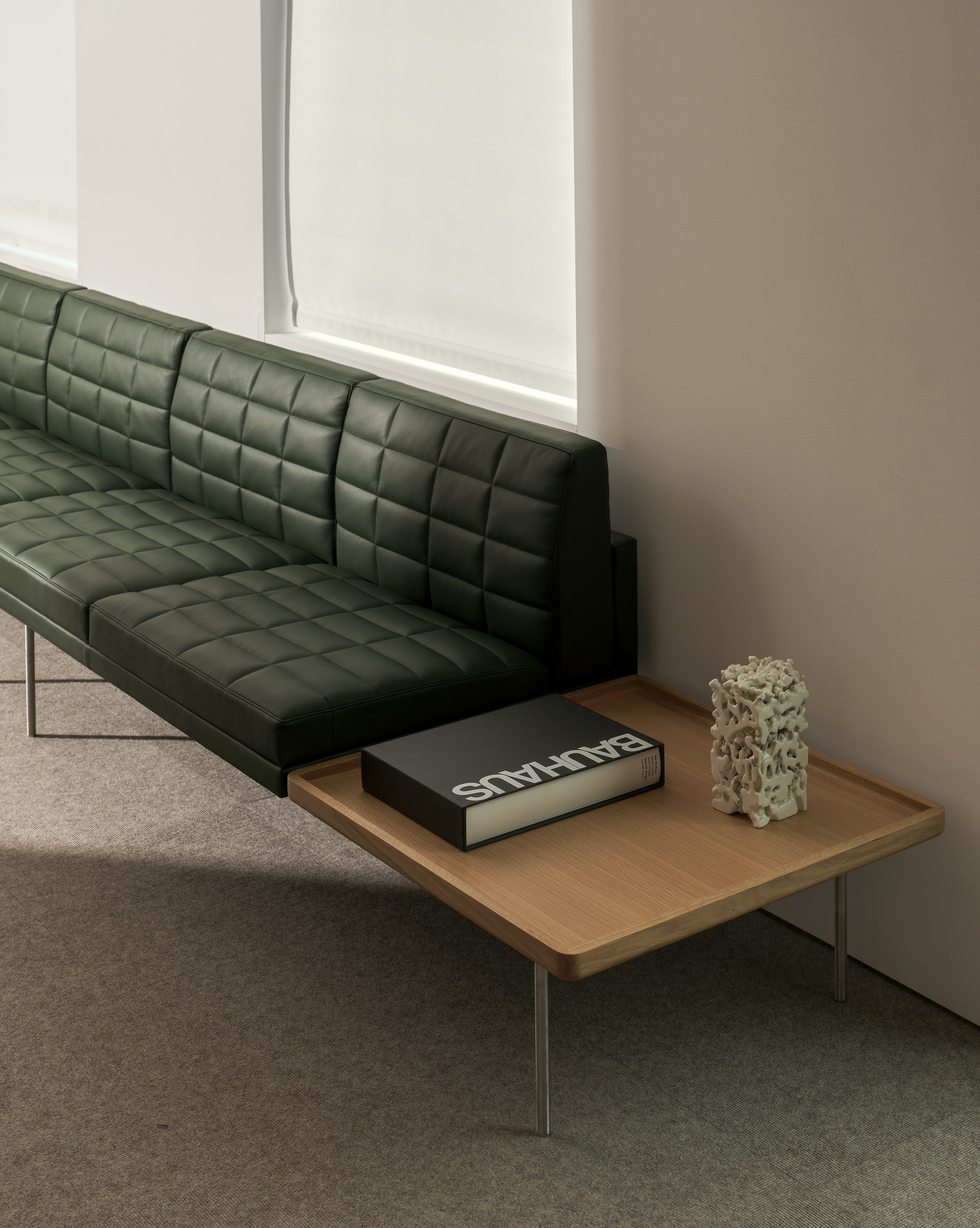 Tuxedo Component Sectional Sofa upholstered with Prone Leather in Vine with an integrated side table in Natural Oak, viewed at an angle.