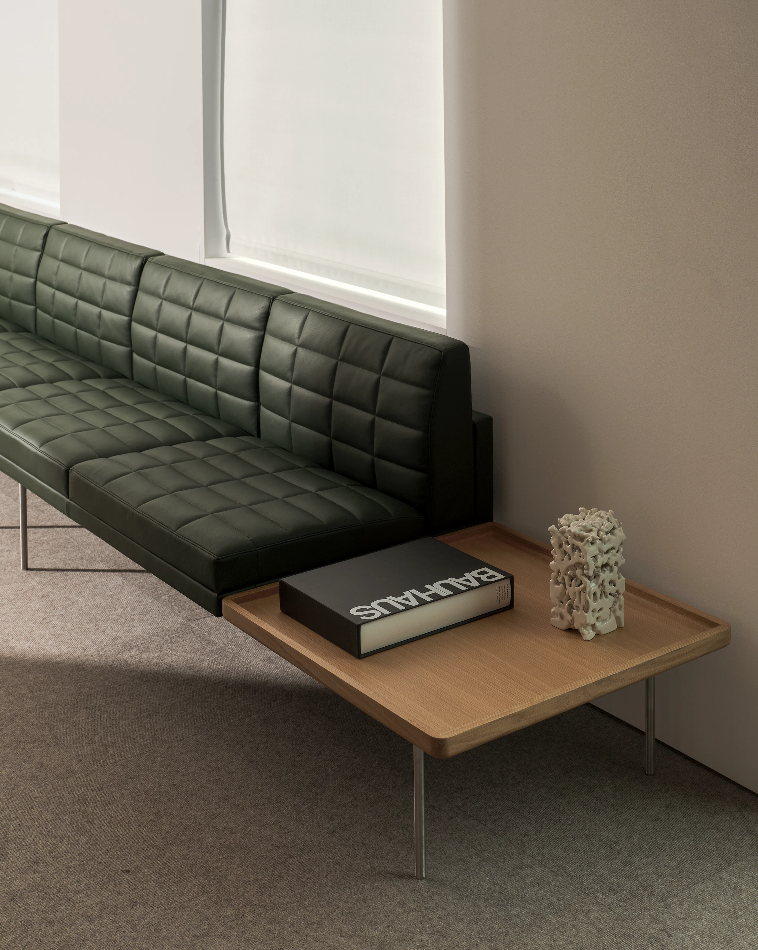 Tuxedo Component Sectional Sofa upholstered with Prone Leather in Vine with an integrated side table in Natural Oak, viewed at an angle.