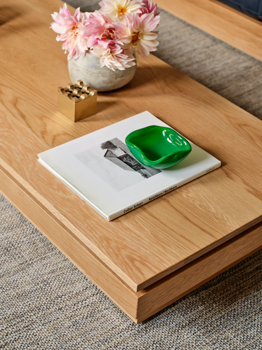 Close-up of wooden coffee table with vase of flowers and magazines