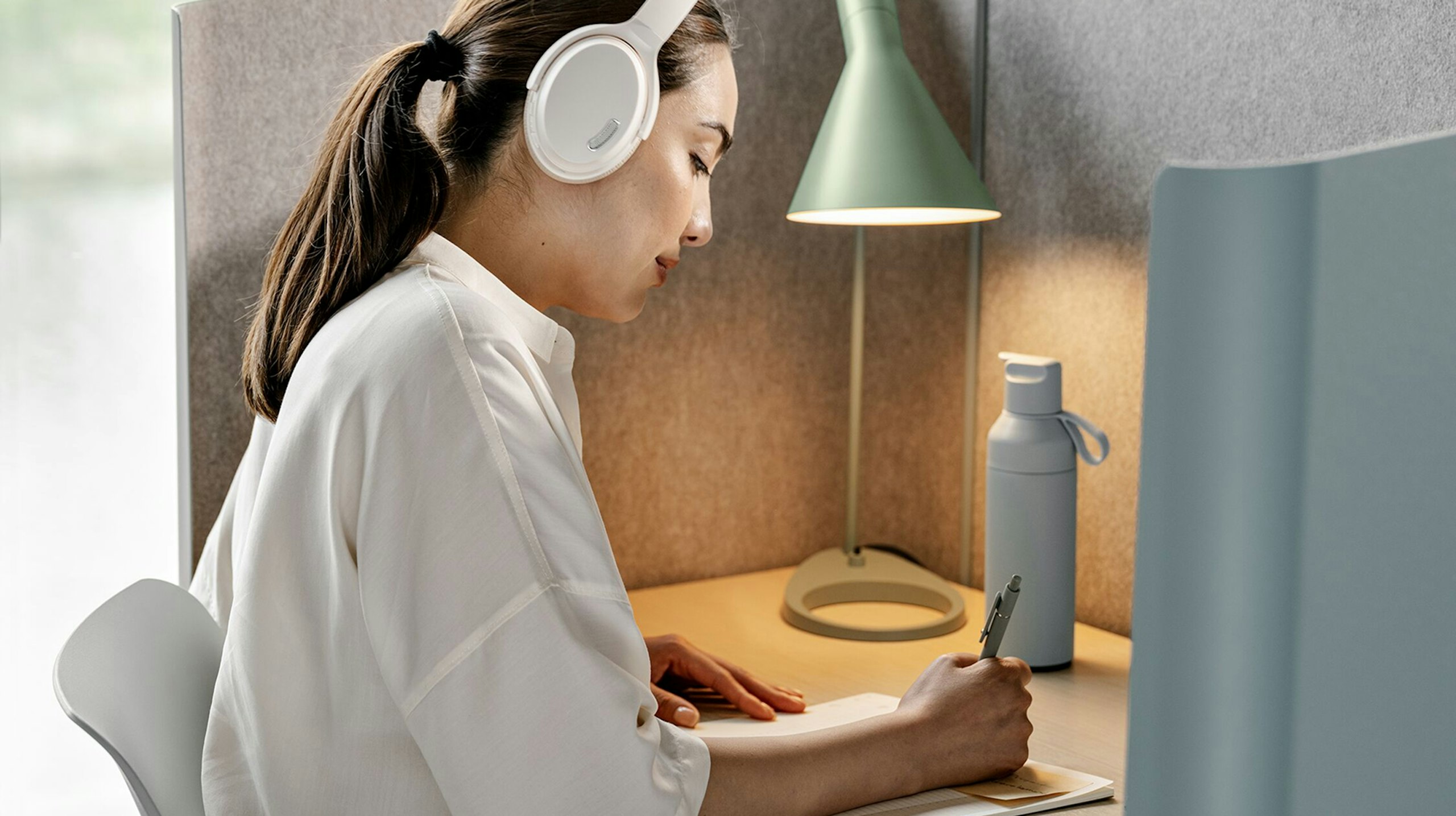 Woman working at a grey Herman Miller Pullman Desk.