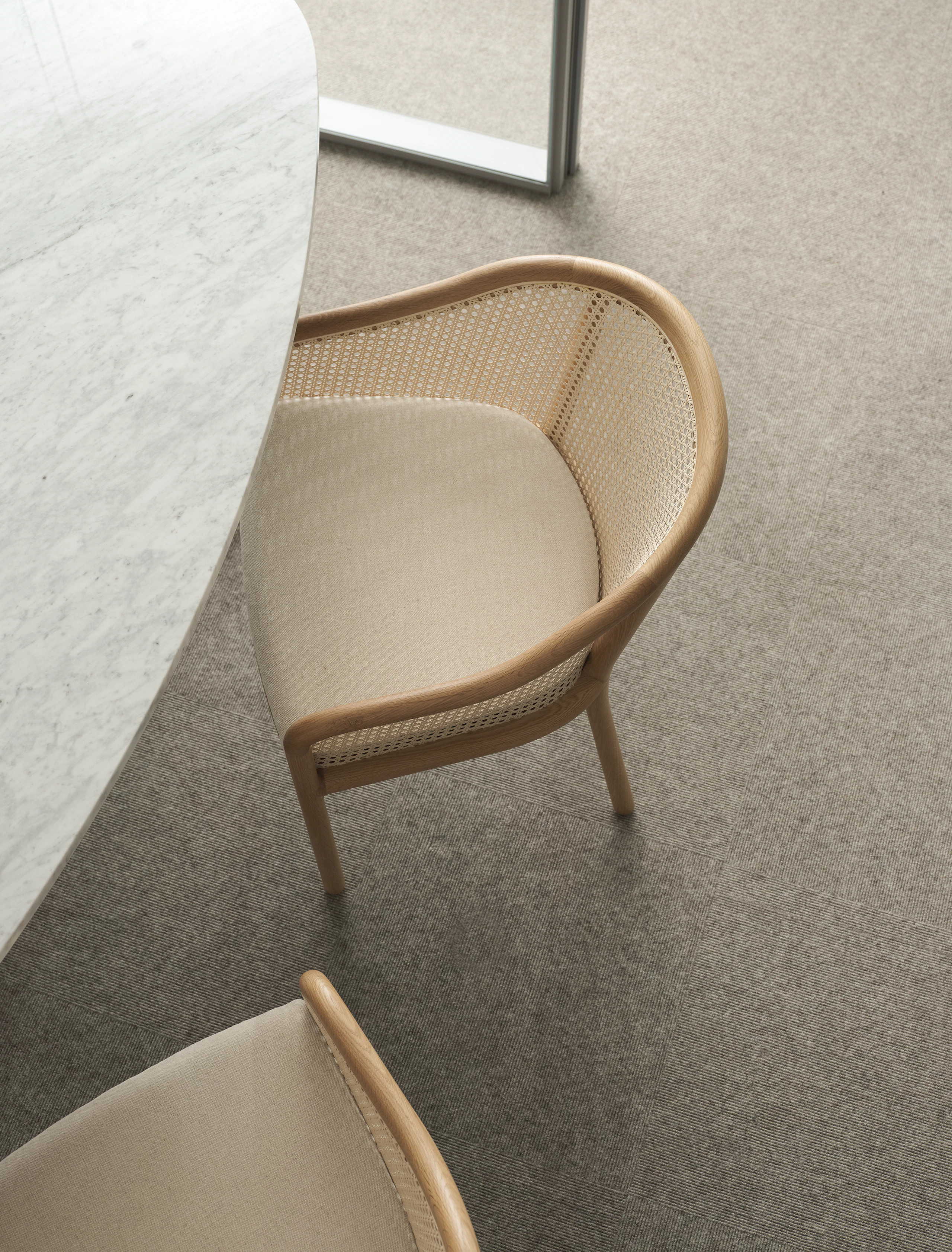 MP Height Adjustable Table in White Carrara Marble with two cane-back Landmark Chairs upholstered with Petra in Dreamy, viewed from above.