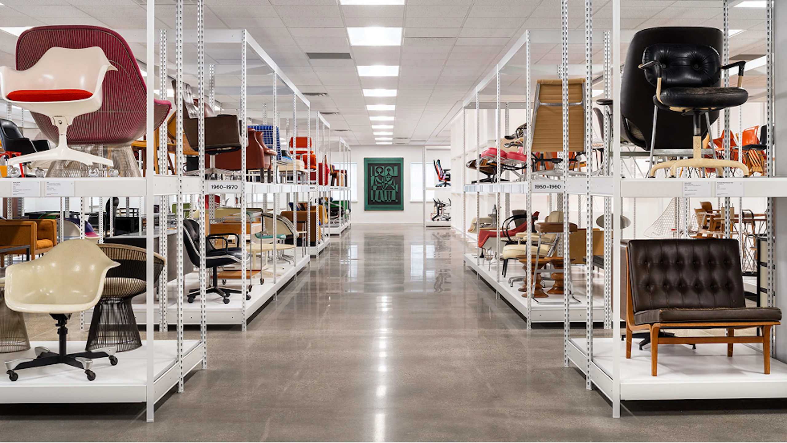 Rows of white display shelves at the MillerKnoll Archives featuring historic pieces of furniture from the MillerKnoll collective of brands