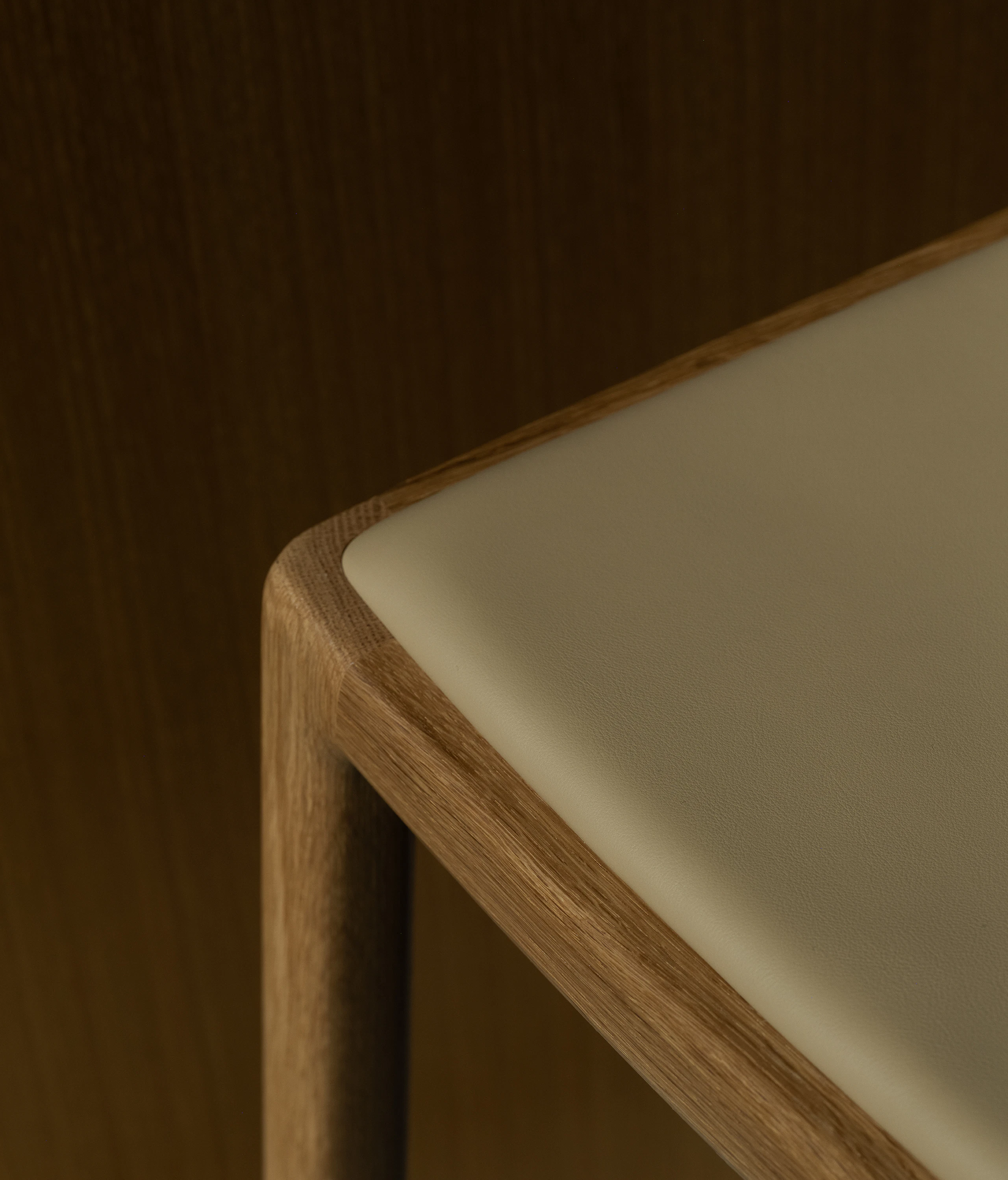 Detail view of a Lijn Stool seat in Natural Oak fully upholstered with Bristol leather in Champagne, viewed from above.