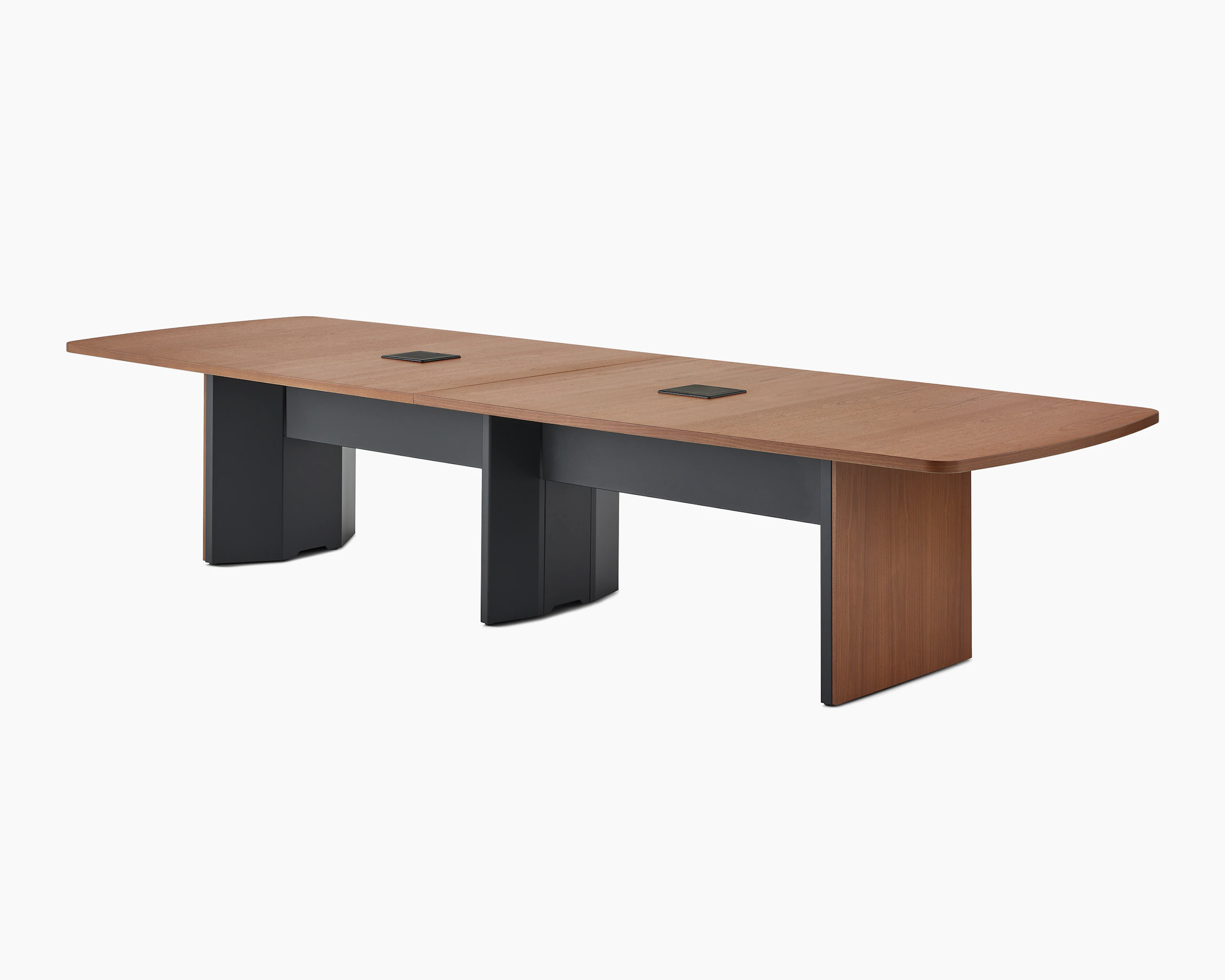 A medium walnut cabinet base Headway conference table viewed at an angle with a black tech curtain underneath.