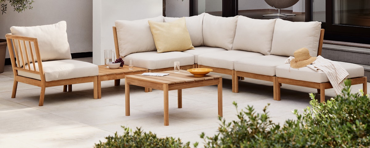 Tradition Outdoor Table in front of an assembled Tradition Outdoor Sofa Sectional in an outdoor patio setting