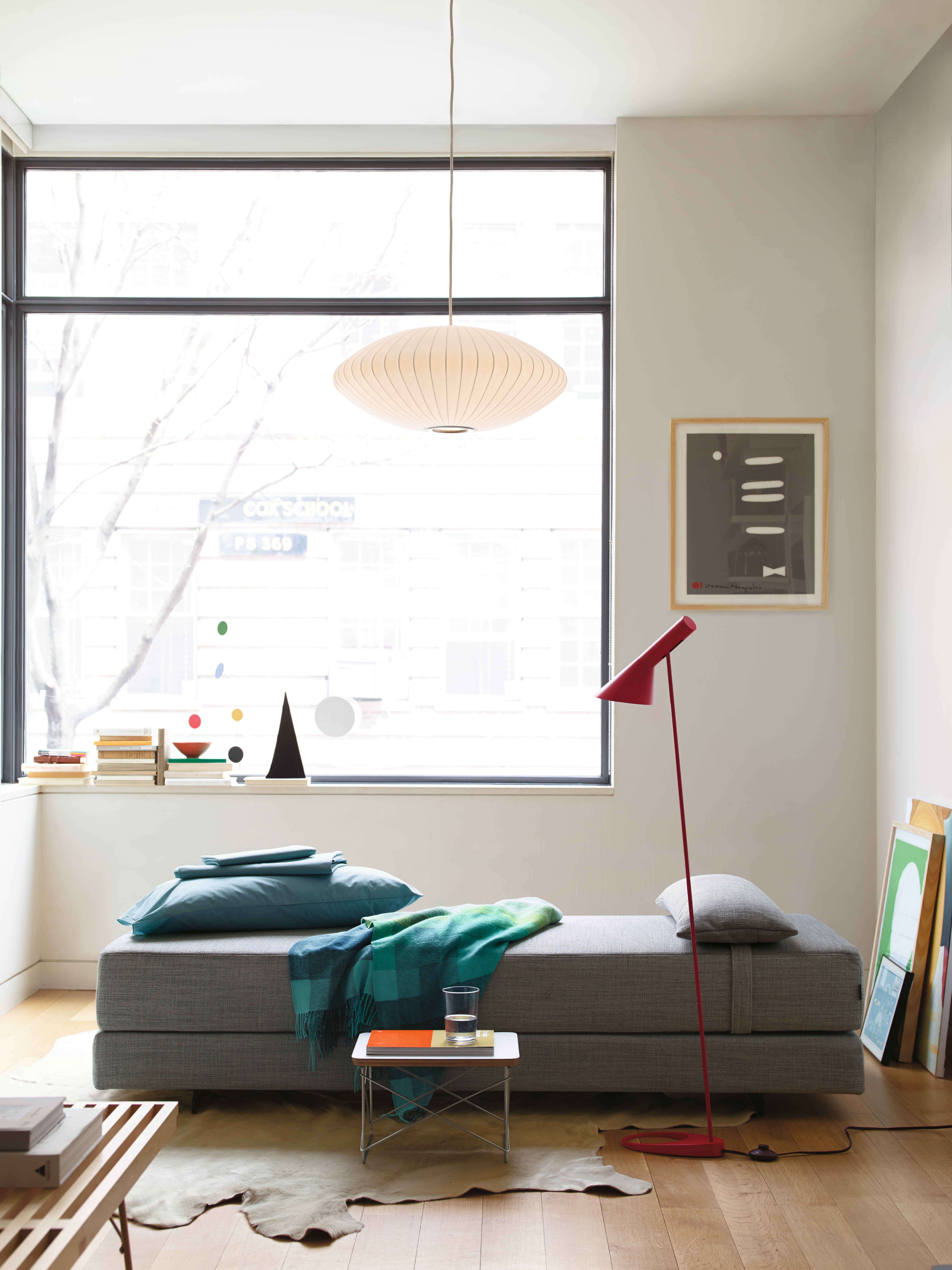 Duet Daybed, AJ Floor Lamp, Eames Wire Base Low Table, and Nelson Saucer Bubble Pendant in a living room setting