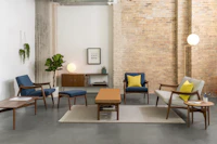 A casual lounge setting with Aspen Lounge Seating with walnut bases, a Tamarack Table and Bench in walnut, and Hemlock tables in walnut.