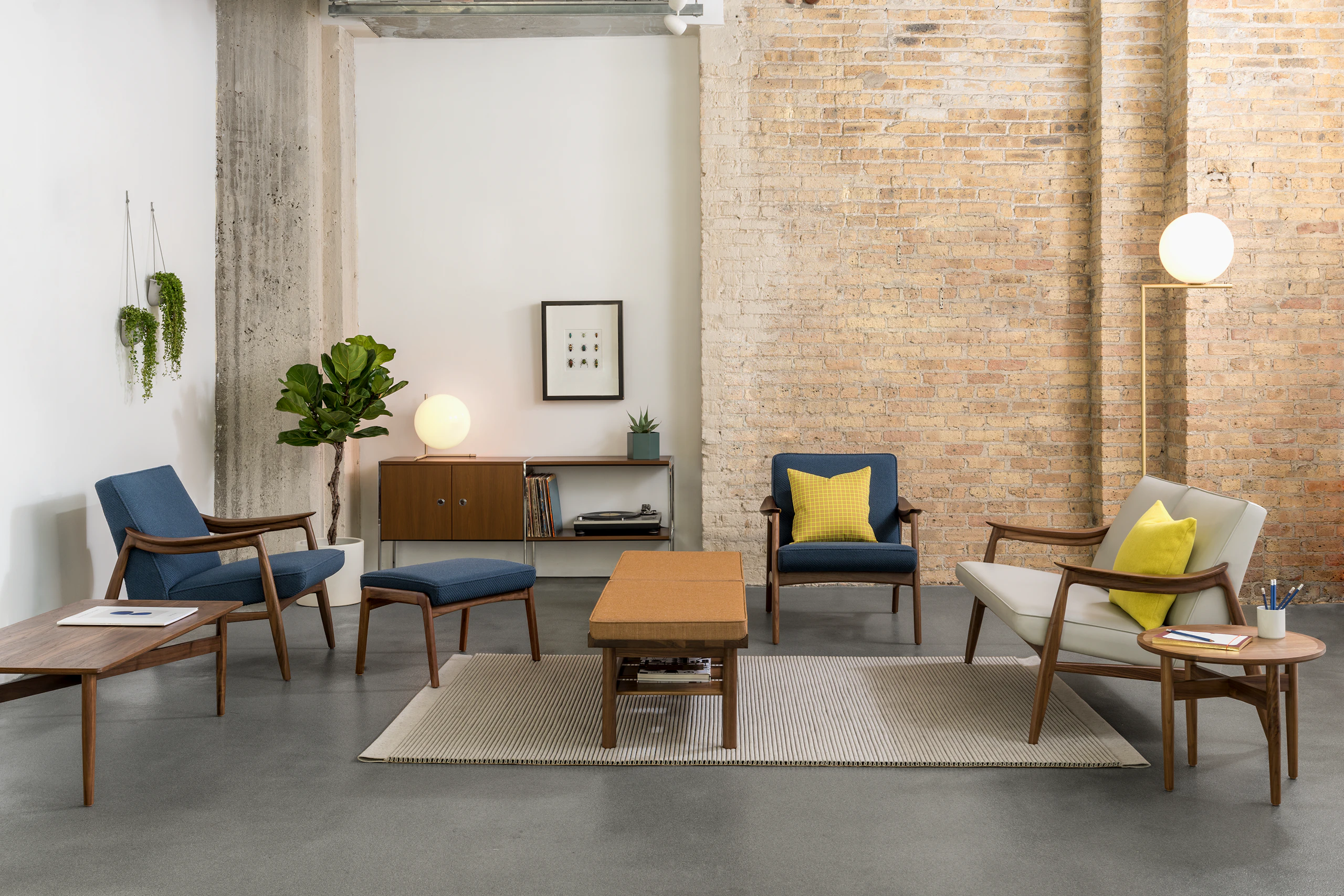A casual lounge setting with Aspen Lounge Seating with walnut bases, a Tamarack Table and Bench in walnut, and Hemlock tables in walnut.