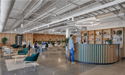 Groups of individuals utilizing an interior communal area and reception desk in the Ledger office space