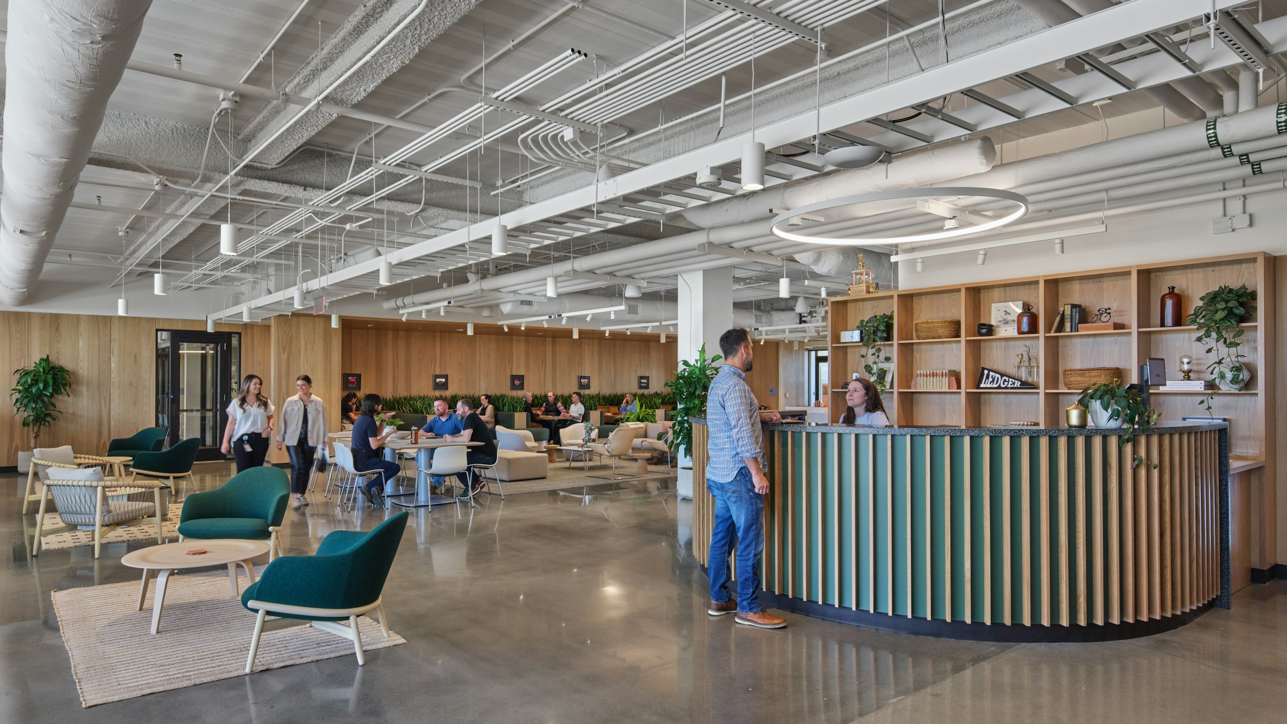 Groups of individuals utilizing an interior communal area and reception desk in the Ledger office space