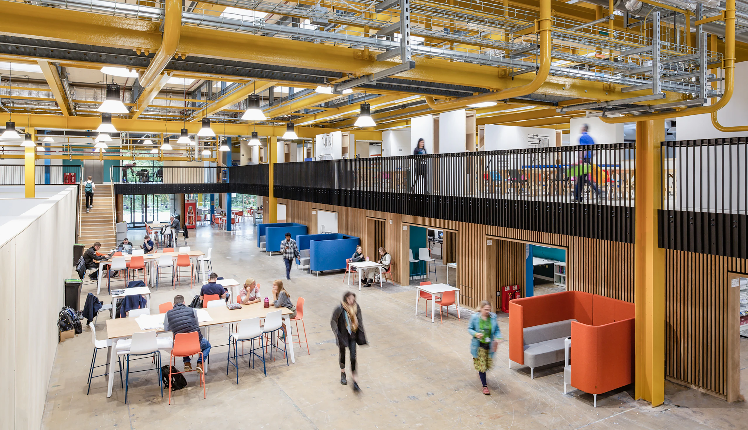 Univeristy campus with working booths down the right side and bar height tables with stools down the left.