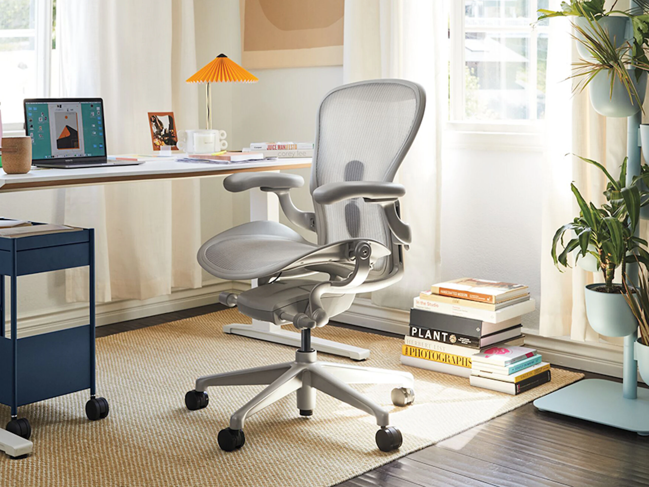 An Aeron Chair with a mineral, polished aluminum finish with a Renew Desk, in a home office.