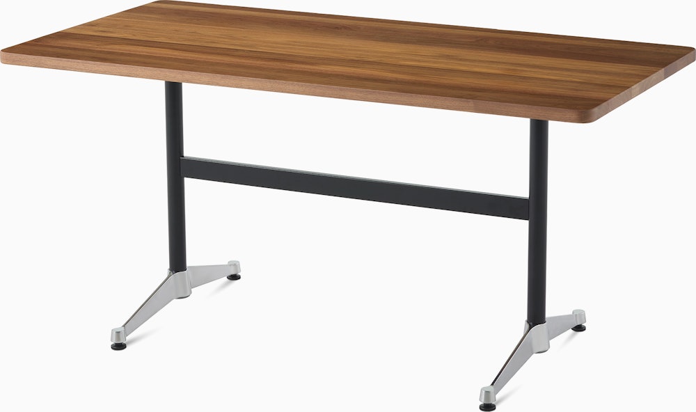 An Eames T-Leg table with a walnut top, black legs, and chrome feet. 