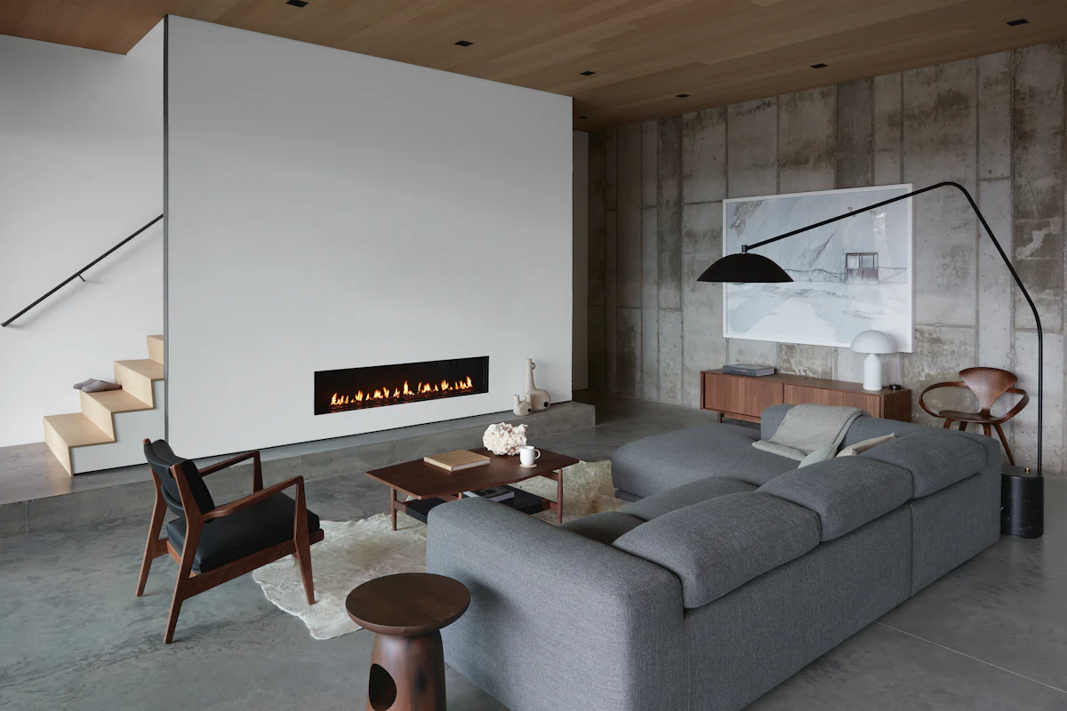 Open living room with gray sectional sofa and wood accents around a modern fireplace