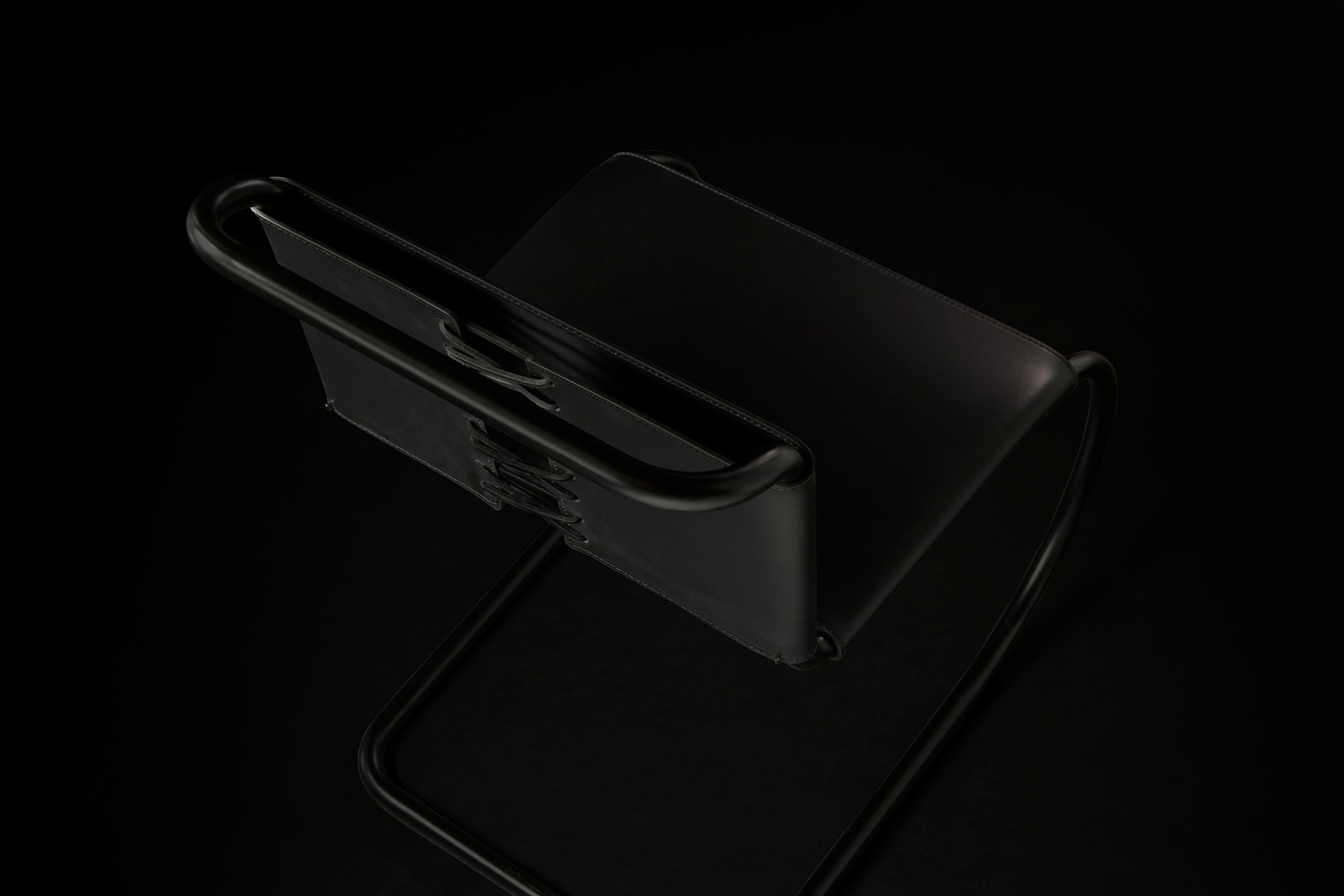 MR Chair Black Leather Armless Detail on Black Background