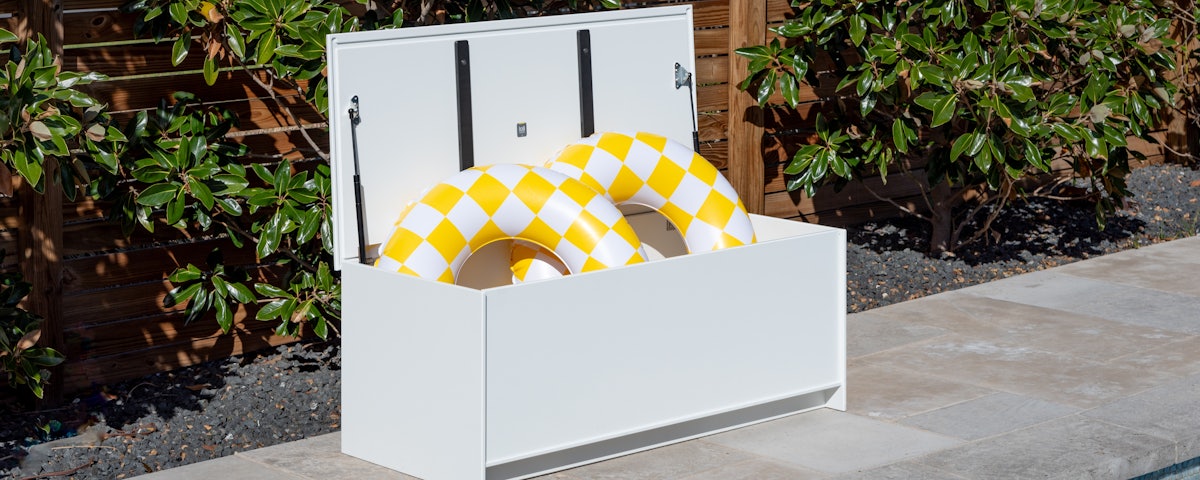 Slider Storage Chest holding swimming pool float tubes at a poolside setting