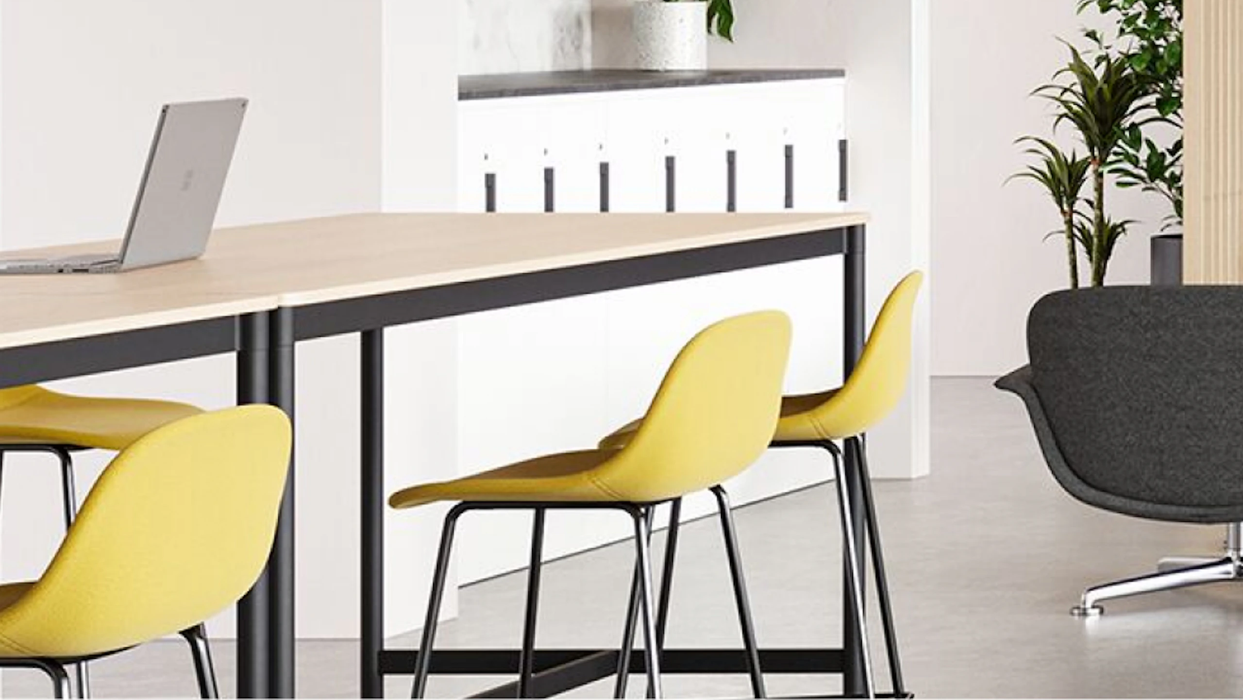 Yellow bar-height stools arranged at a Muuto Base Table used to encourage connection in a community café setting