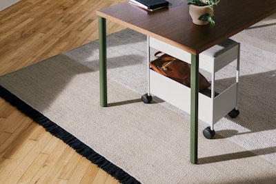 A grey, individual OE1 Storage Trolley with castors, nesting under an OE1 Rectangular Table with dark brown surface and green legs.