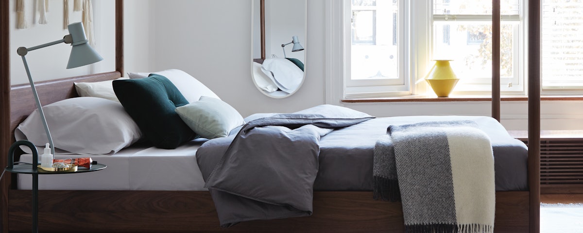 Type 80 Desk Lamp on a bedside table next to a Cove Canopy Bed in a bedroom setting