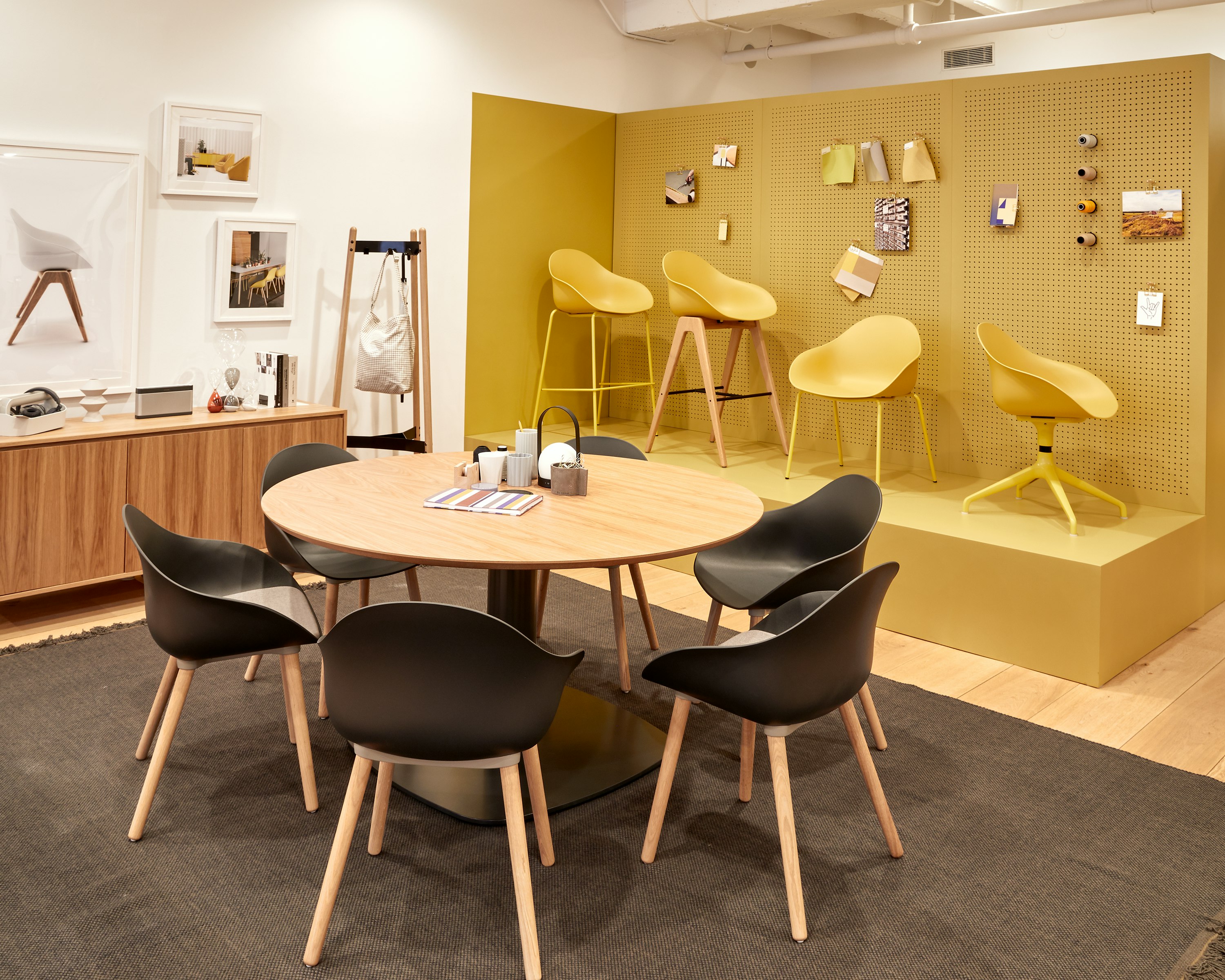 Six black Ruby chairs with oak dowel legs, around a Megaped Table with an oak veneer Sideboard, oak Hudson Coat Stand and yellow Ruby chairs.