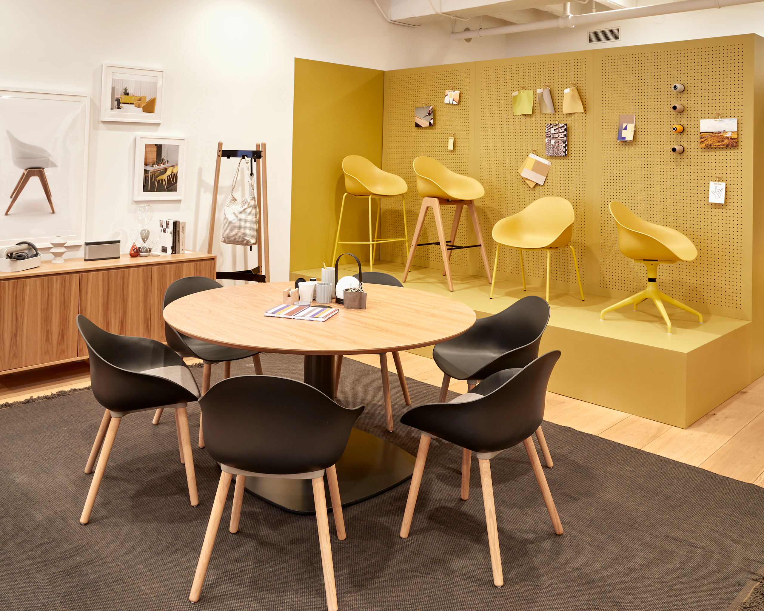 Six black Ruby chairs with oak dowel legs, around a Megaped Table with an oak veneer Sideboard, oak Hudson Coat Stand and yellow Ruby chairs.