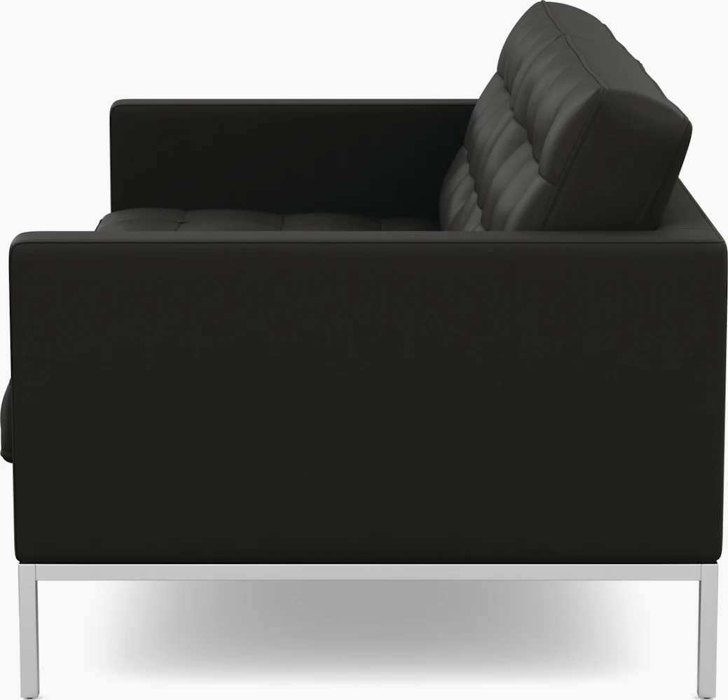 Modern living room with black leather sofa, glass coffee table, and shag rug.