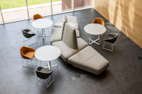An overhead view of a beige naughtone Rhyme Modular Seating arrangement paired with three white Frog Café tables and gray and orange Always Chairs.