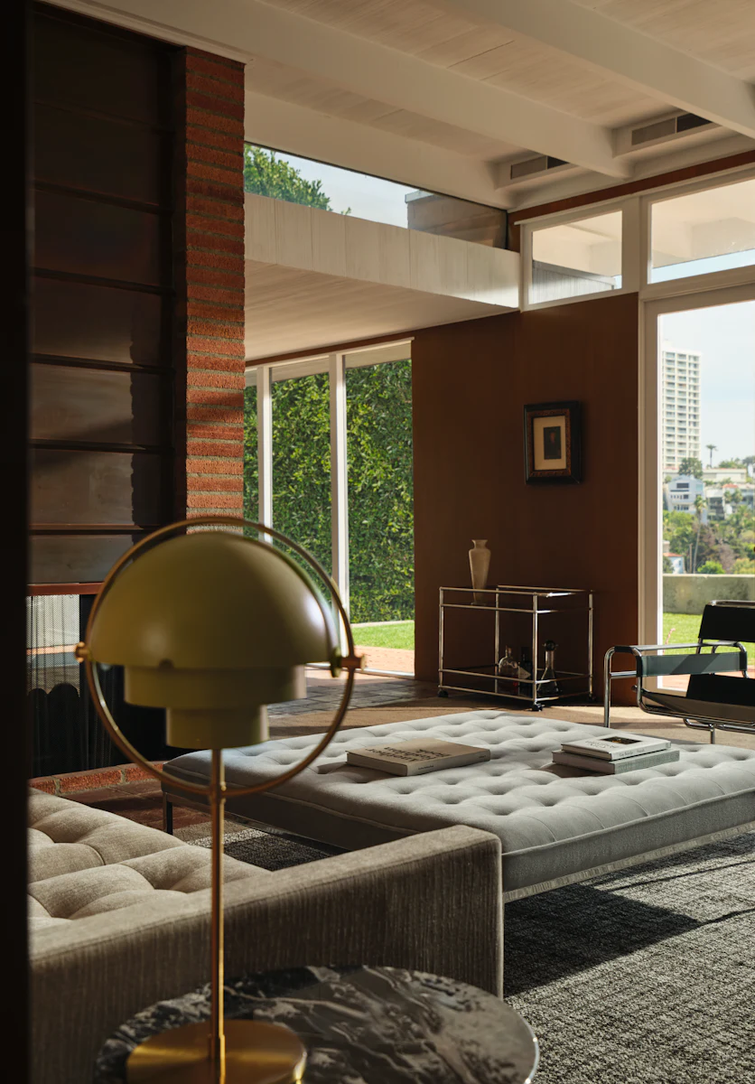 Wide view of living room with brick fireplace, seating, and large glass doors to outside.